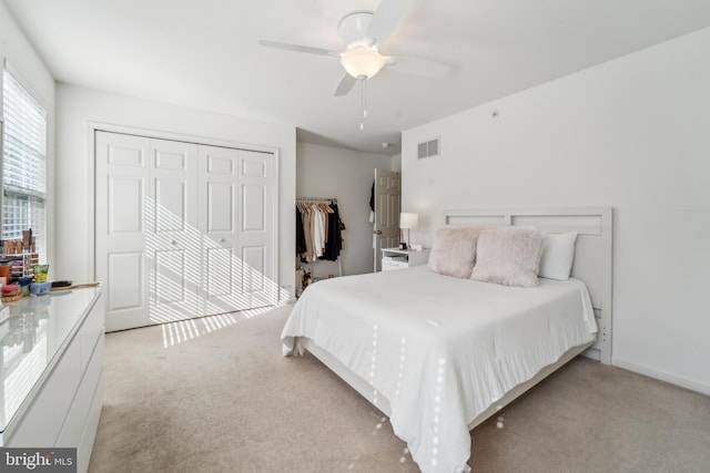 bedroom featuring a ceiling fan, visible vents, a closet, and light colored carpet