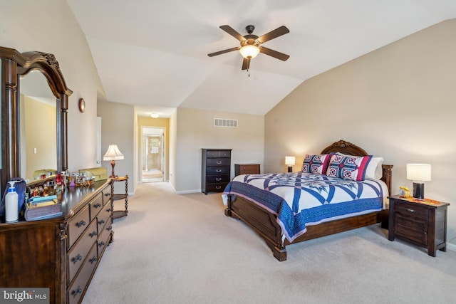 bedroom with ceiling fan, ensuite bathroom, light colored carpet, visible vents, and vaulted ceiling