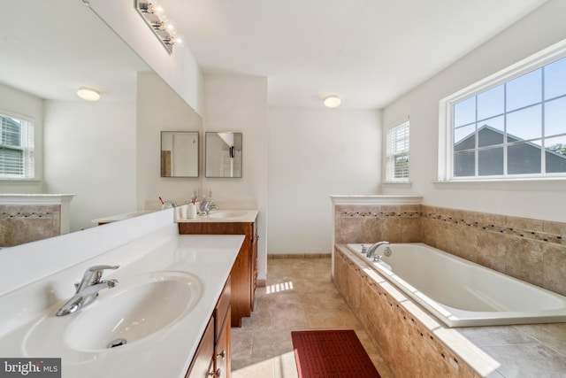 full bath with a bath, baseboards, two vanities, and a sink