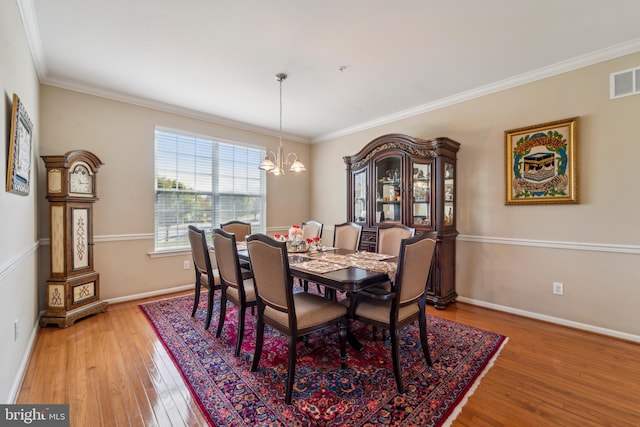 dining area with visible vents, baseboards, wood finished floors, an inviting chandelier, and crown molding