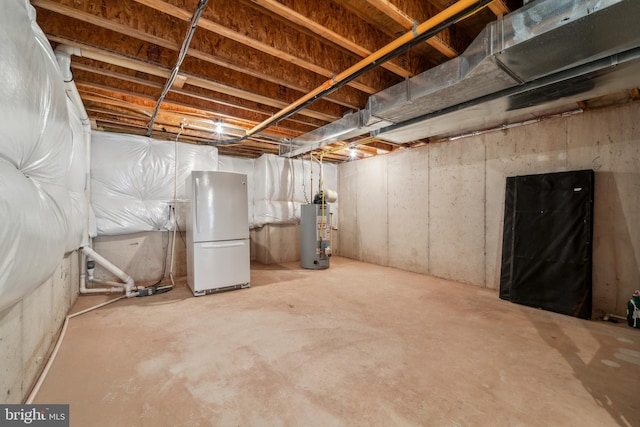 unfinished below grade area featuring freestanding refrigerator and gas water heater