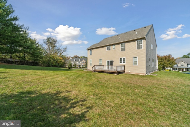 back of house with a deck and a lawn