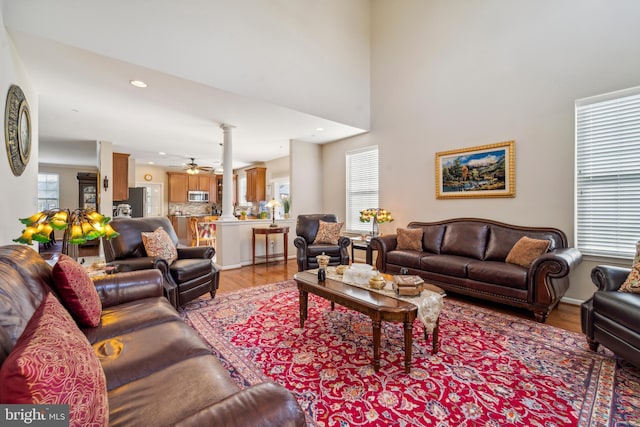 living area with ornate columns, light wood-style flooring, a ceiling fan, and recessed lighting