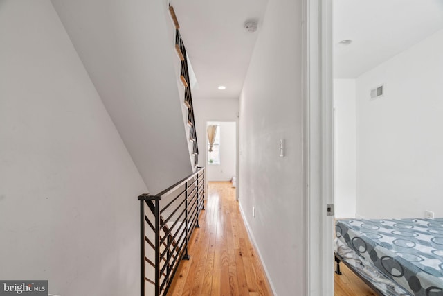 hallway featuring light wood finished floors, visible vents, and baseboards