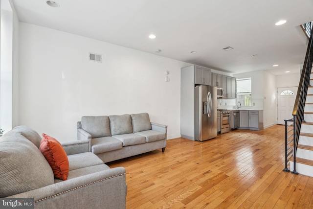 living room featuring stairway, visible vents, light wood-style floors, and recessed lighting