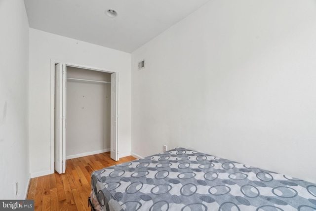 bedroom with light wood-type flooring, visible vents, and baseboards