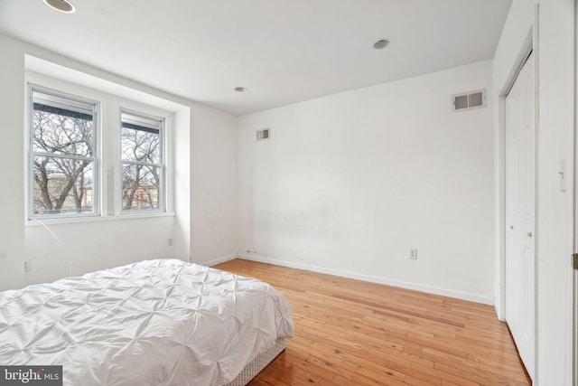 bedroom featuring light wood-style floors, visible vents, and baseboards