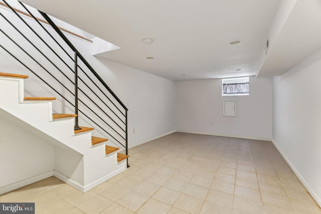 below grade area featuring baseboards and stairs