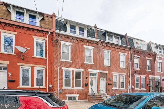 townhome / multi-family property with roof with shingles, brick siding, and mansard roof