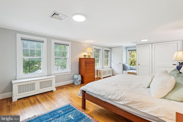 300 E Broad St, Falls Church, VA 22046 - bedroom featuring radiator heating unit, wood finished floors, and multiple windows