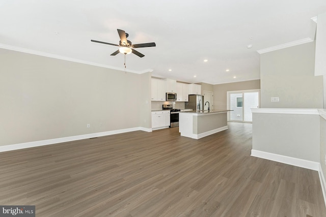 unfurnished living room featuring dark wood-style floors, baseboards, ornamental molding, and a sink