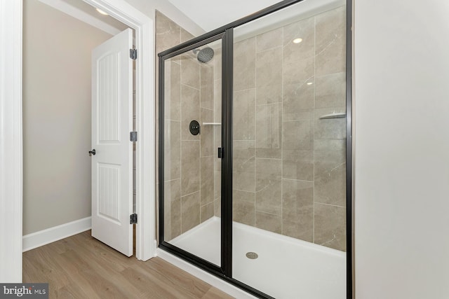 full bath featuring a stall shower, wood finished floors, and baseboards