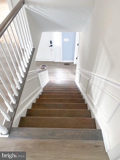 stairway featuring wood finished floors and a decorative wall