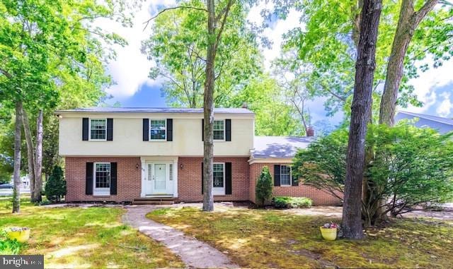 colonial-style house with brick siding and a front lawn