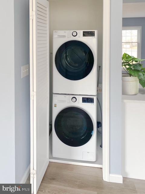 laundry area featuring laundry area, light wood-style flooring, and stacked washer and clothes dryer