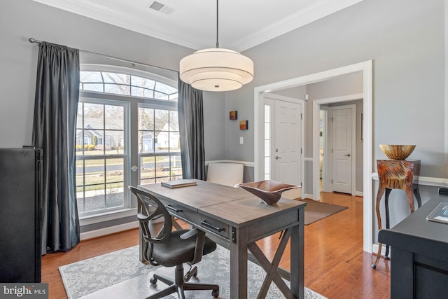 office area with baseboards, visible vents, wood finished floors, and ornamental molding