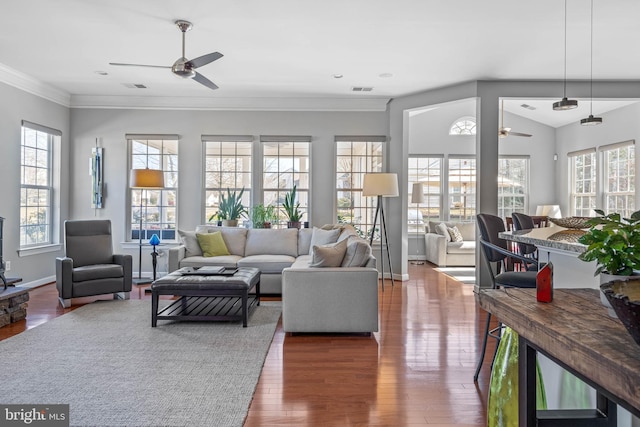 living area featuring a wealth of natural light, ceiling fan, ornamental molding, and wood finished floors