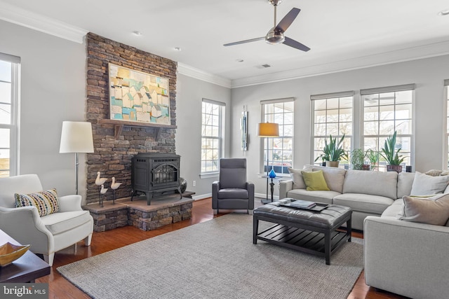 living area with a wood stove, visible vents, wood finished floors, and ornamental molding