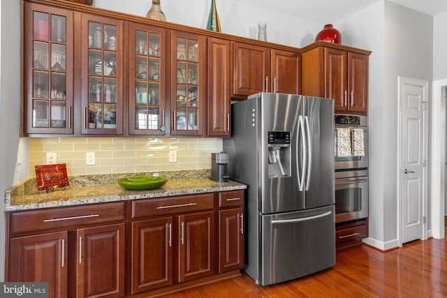 kitchen featuring stainless steel appliances, dark wood-type flooring, glass insert cabinets, and backsplash