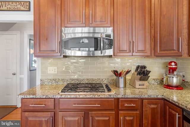 kitchen featuring light stone countertops, stainless steel appliances, and decorative backsplash