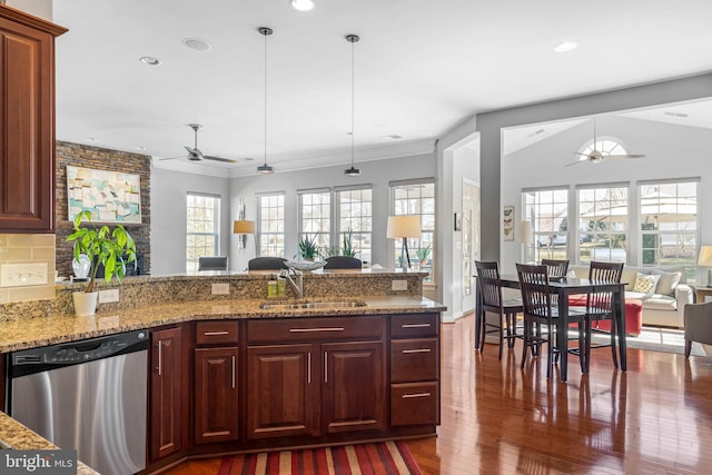 kitchen featuring open floor plan, a healthy amount of sunlight, a sink, wood finished floors, and dishwasher