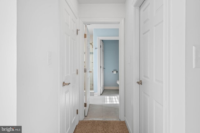 hallway with baseboards and carpet flooring