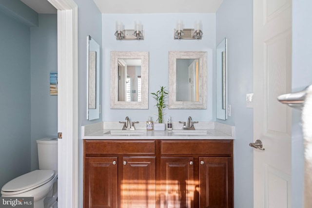 bathroom featuring double vanity, a sink, and toilet