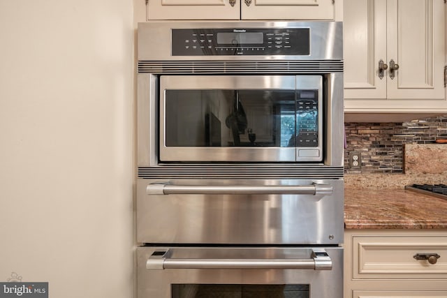 room details with double oven, light stone counters, backsplash, and white cabinets