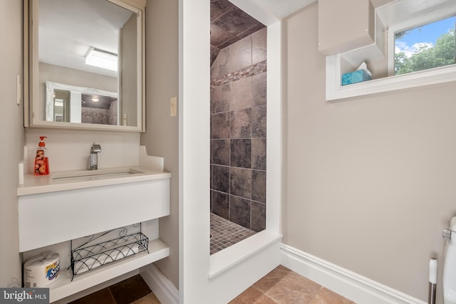 full bath featuring a stall shower, baseboards, and a sink