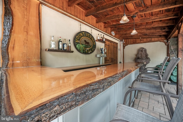 bar with decorative light fixtures, a dry bar, stone tile flooring, wood ceiling, and beamed ceiling