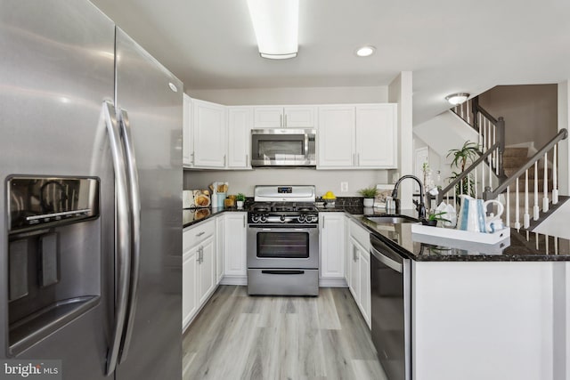 kitchen featuring stainless steel appliances, white cabinetry, a sink, and a peninsula