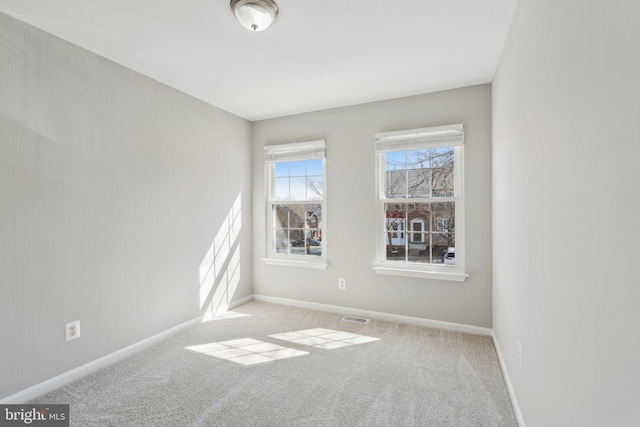 carpeted spare room with visible vents and baseboards