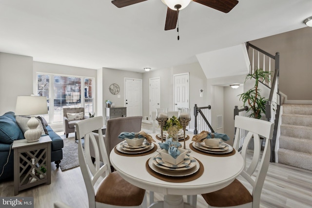 dining space with light wood-style floors, ceiling fan, stairway, and visible vents