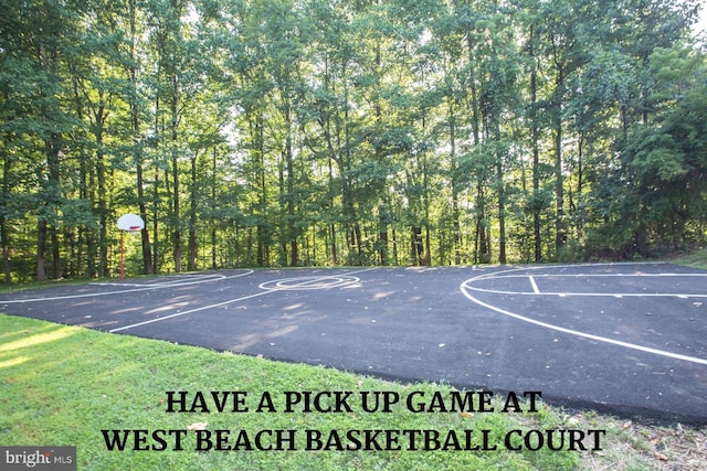 view of basketball court with community basketball court and a wooded view