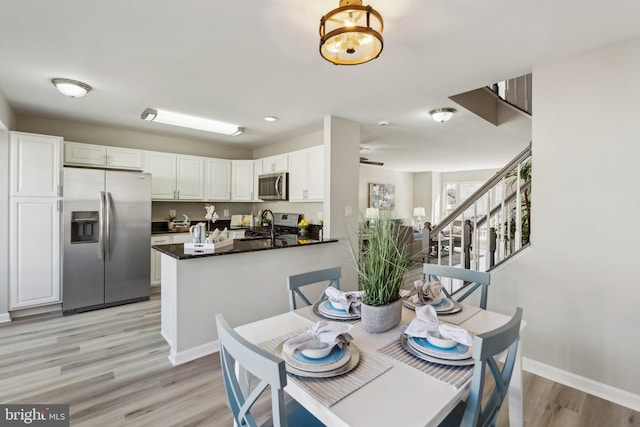 dining space featuring baseboards, ceiling fan, stairs, and light wood-style floors