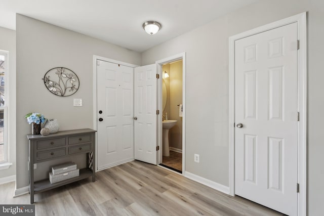 bedroom featuring a closet, ensuite bath, light wood-style flooring, and baseboards