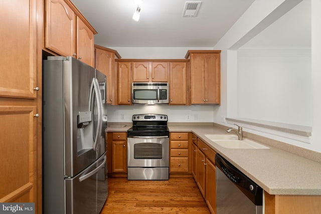 kitchen with light wood-style flooring, a sink, visible vents, light countertops, and appliances with stainless steel finishes