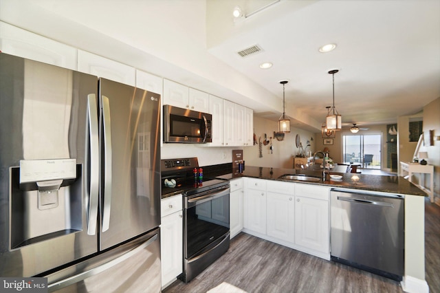 kitchen featuring stainless steel appliances, dark countertops, visible vents, white cabinets, and a peninsula