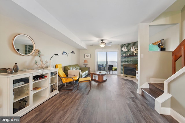 sitting room featuring dark wood-style floors, a fireplace, stairway, ceiling fan, and baseboards