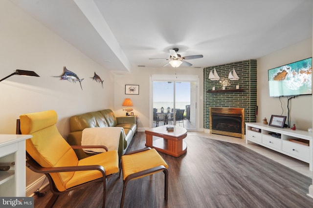 living room with a brick fireplace, baseboards, a ceiling fan, and wood finished floors