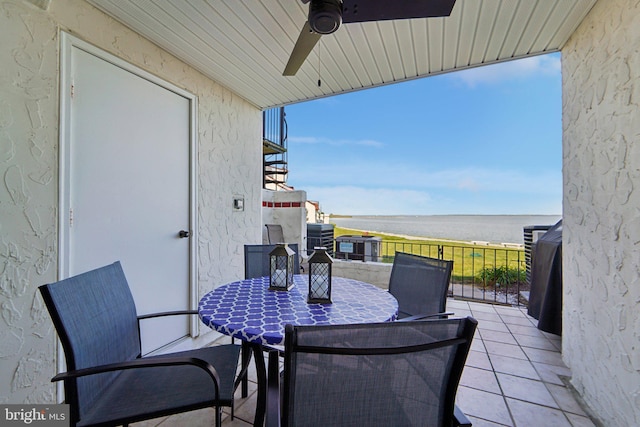 balcony featuring a water view, a sunroom, a ceiling fan, and outdoor dining space