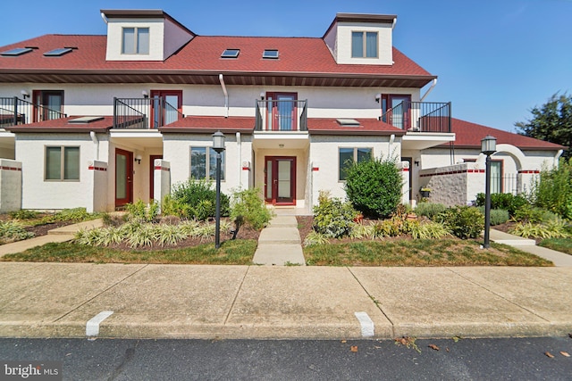 multi unit property featuring a balcony, a shingled roof, and stucco siding