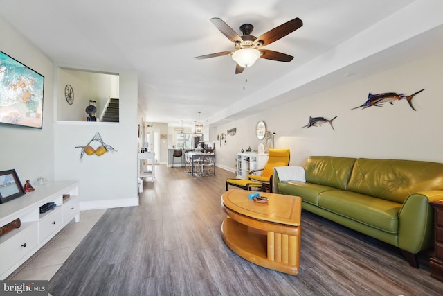 living area featuring ceiling fan, baseboards, and wood finished floors