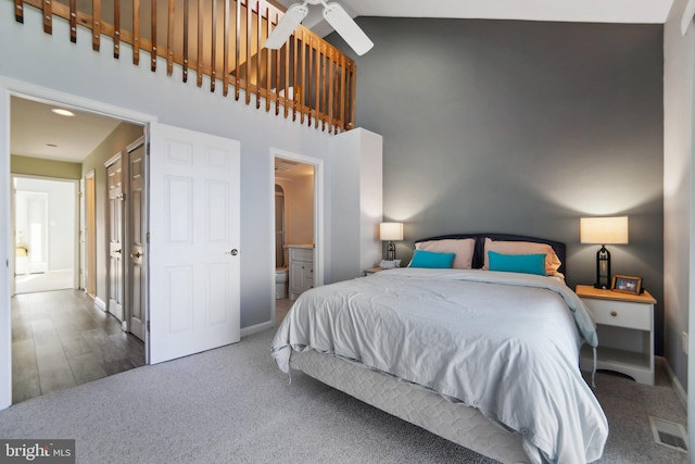 bedroom with high vaulted ceiling, visible vents, connected bathroom, and baseboards