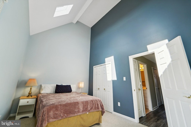 bedroom with high vaulted ceiling, a skylight, baseboards, a closet, and beam ceiling