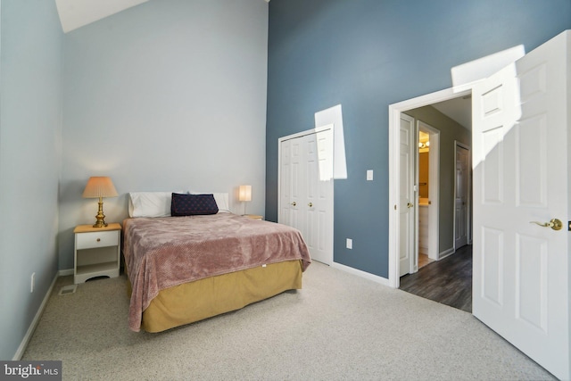 bedroom with a closet, a high ceiling, dark carpet, and baseboards