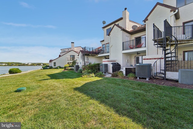 view of yard with stairs, central AC, and a water view