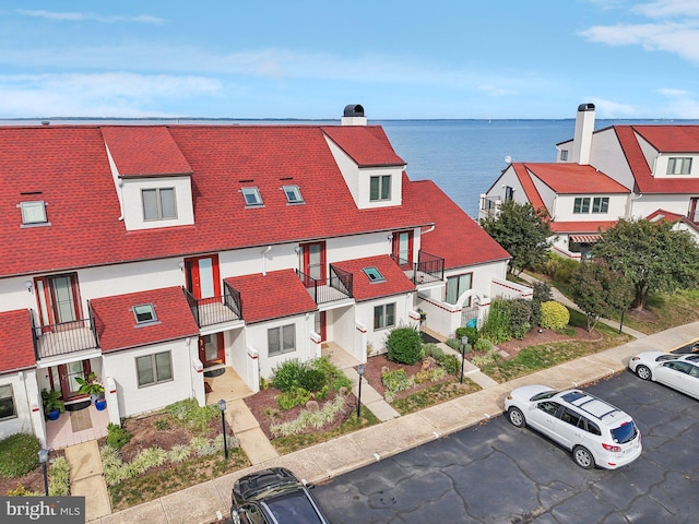 exterior space featuring uncovered parking, a water view, and a residential view