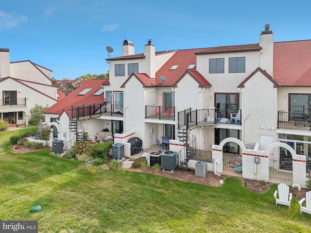 back of property with central AC, a lawn, a chimney, and stucco siding