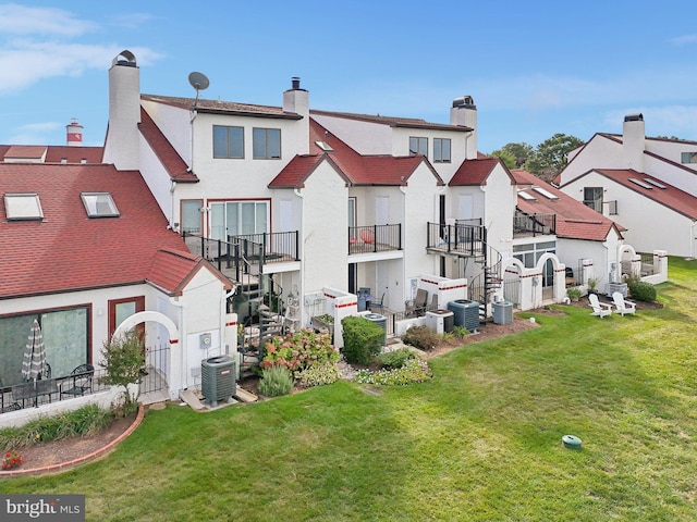 back of house with a residential view, a lawn, and central air condition unit